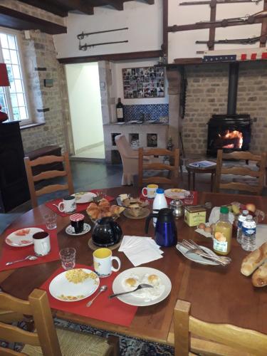 - une table avec de la nourriture et une cheminée dans l'établissement Sainte-Mère-Église - Ferme de Beauvais, à Sainte-Mère-Église