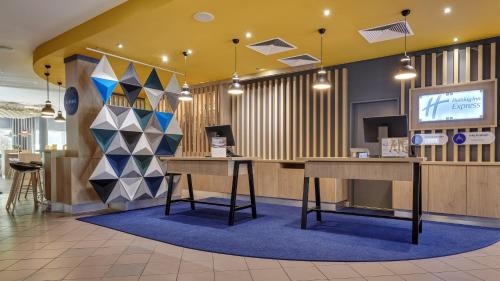 a lobby with a desk and a tv on a wall at Holiday Inn Express Cologne Troisdorf by IHG in Troisdorf