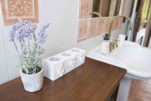 un baño con un jarrón con flores púrpuras sobre una mesa en Alloggio vocabolo San Sebastiano, en Massa Martana