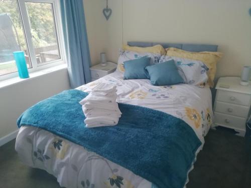 uma cama com um cobertor azul e almofadas azuis em Wedgewood Annexe - All the comforts of home em Mere