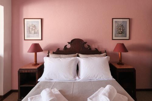 a bedroom with pink walls and a bed with white pillows at Home of pilgrims d`Apúlia in Apúlia