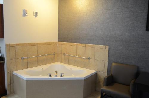 a bathroom with a bath tub and a chair at Holiday Inn Express Hotel & Suites Barstow by IHG in Barstow