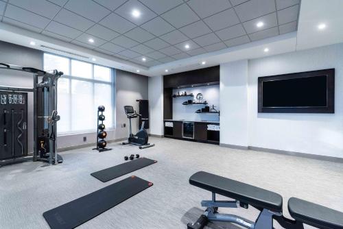 a gym with cardio equipment and a flat screen tv at Staybridge Suites - Quincy by IHG in Quincy
