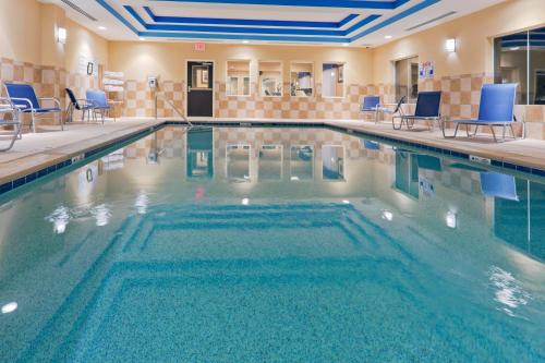 a large swimming pool with blue chairs in a building at Holiday Inn Express Columbia by IHG in Columbia