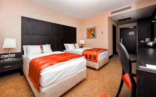 a hotel room with two beds and a desk at Holiday Inn Trnava by IHG in Trnava