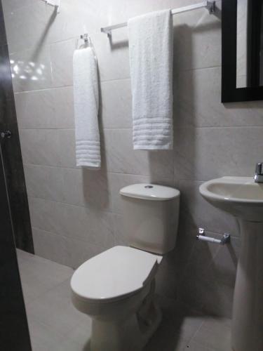 a bathroom with a toilet and a sink with towels at Casa Hotel Manga Mar in Cartagena de Indias