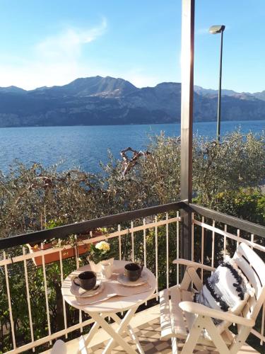 a table and chairs on a balcony with a view of the water at Villa sul Lago con pontile privato a Brenzone sul Garda - Unique and exclusive in Brenzone sul Garda