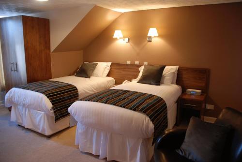 a hotel room with two beds and two lamps at Kirklands Hotel in Kinross