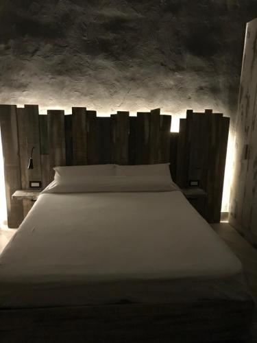 サン・ジョルジョ・ア・クレマーノにあるDomus Vesuvioの木製ヘッドボード付きの客室の白いベッド1台