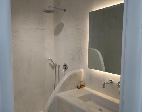 W białej łazience znajduje się umywalka i lustro. w obiekcie Kritamos suites w mieście Iraklia