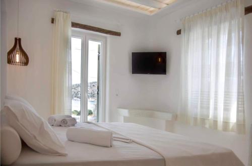 a white bedroom with a large bed with a window at Kritamos suites in Iraklia