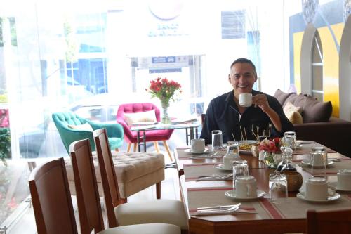 a man sitting at a table with a cup of coffee at Hotel Carolina Montecarlo in Quito