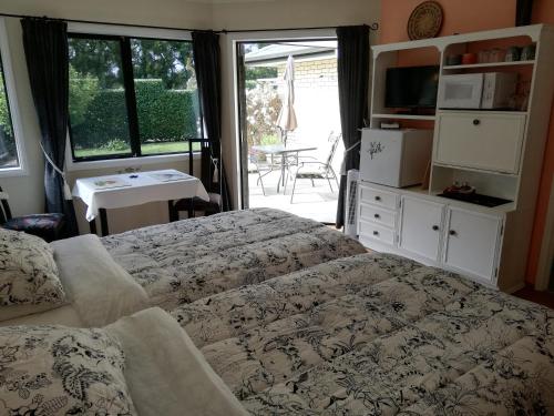 a bedroom with two beds and a view of a patio at The Little Gem in Waitara