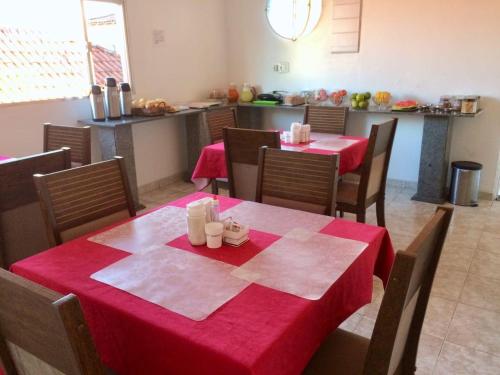 uma sala de jantar com duas mesas e cadeiras com toalha de mesa vermelha em Pousada Pinheiro em Campos dos Goytacazes
