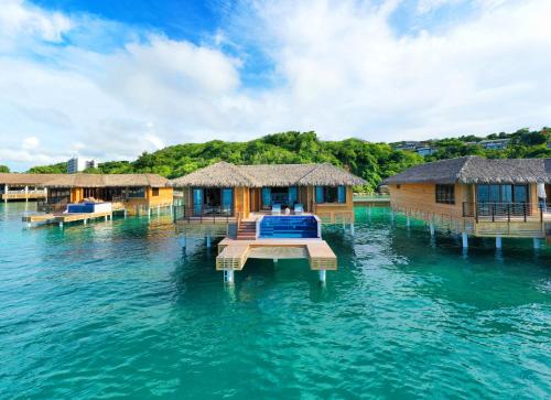 a group of overwater bungalows in the water at Royalton Antigua, An Autograph Collection All-Inclusive Resort in Five Islands Village
