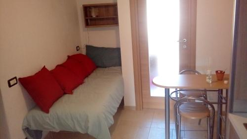 a room with a bed with red pillows and a table at La maison de Martine in Bolognano