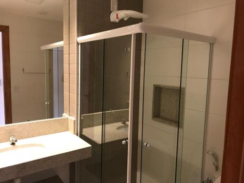 a bathroom with a glass shower and a sink at Vilage beira mar in Itacimirim