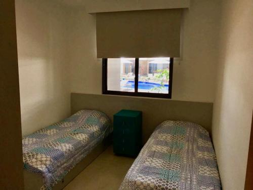 two beds in a room with a window at Vilage beira mar in Itacimirim