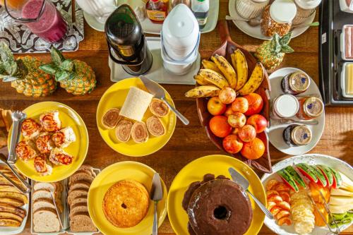 einen Tisch mit Teller mit Lebensmitteln und Obst in der Unterkunft Charme da Vila Suítes in Porto De Galinhas