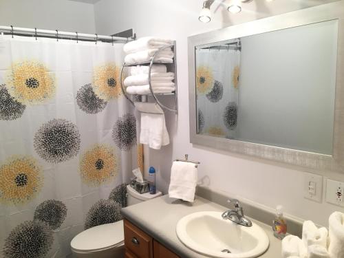 Un baño con lavabo, inodoro y espejo. en Le Milka II, en Longueuil