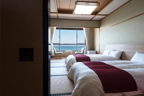 two beds in a room with a view of the ocean at Oarai Hotel Annex Gyoraian in Oarai