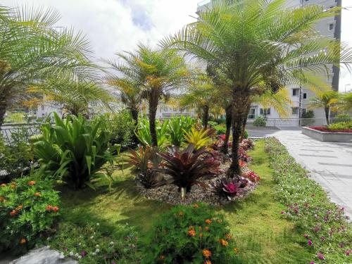 a garden in front of a building with palm trees and flowers at The Quintet, Tower Ethel in Tanah Rata