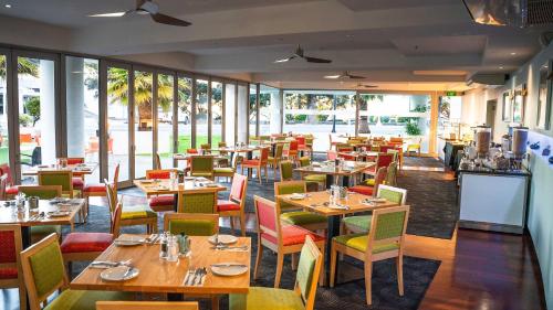 
a restaurant with tables, chairs, and tables in it at Scenic Hotel Te Pania in Napier
