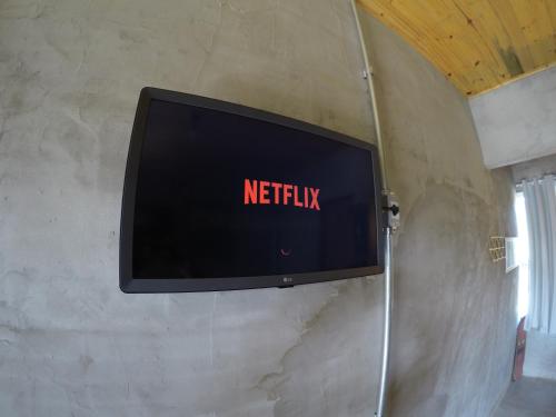 une télévision avec le mot netflix sur un mur dans l'établissement Suítes The Search Ubatuba Surf - Maranduba, à Ubatuba