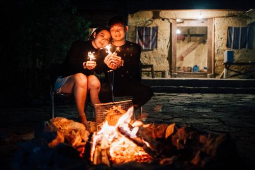 a man and woman sitting next to a fire at Homie homestay in Loung Co