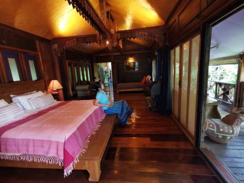 a woman sitting on a bed in a room at BaanBooLoo Village in Chiang Mai