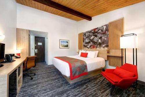 a hotel room with a bed and a desk and chair at Ramada by Wyndham Santa Barbara in Santa Barbara