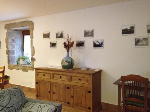 a room with a vase on a wooden cabinet with pictures on the wall at Alojamiento Pazos in Cea
