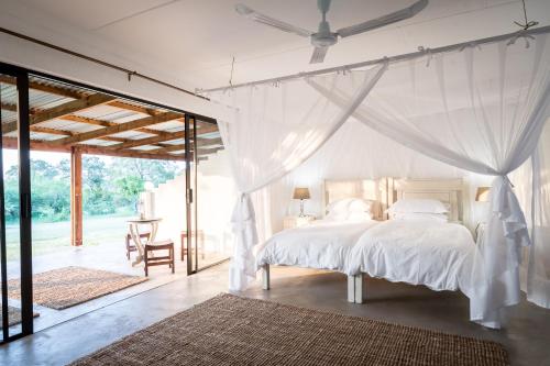 a bedroom with a white bed with a ceiling fan at Makuwa Safari Lodge in Mbabat