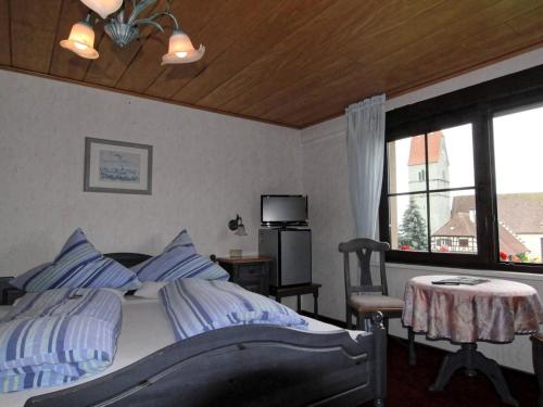 a bedroom with a bed and a table and a window at Gästehaus Ainser in Hagnau