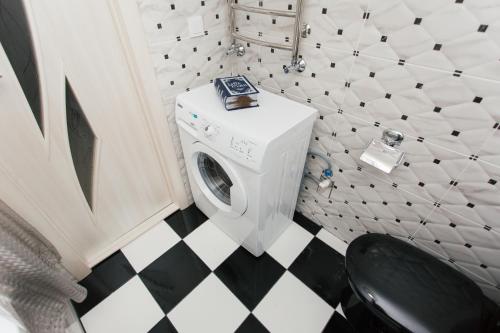 a washing machine in a bathroom with a black and white floor at De LUXE Apartments Centr Illinskaya in Sumy