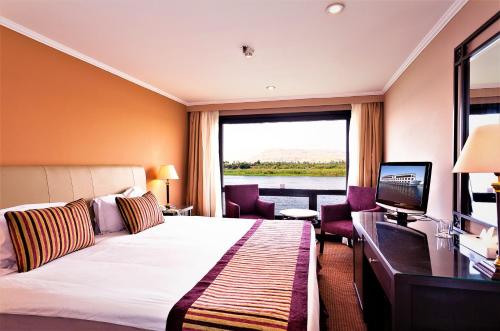ein Hotelzimmer mit einem Bett und einem großen Fenster in der Unterkunft Jaz Crown Prince Nile Cruise - Every Monday from Luxor for 07 & 04 Nights - Every Friday From Aswan for 03 Nights in Luxor