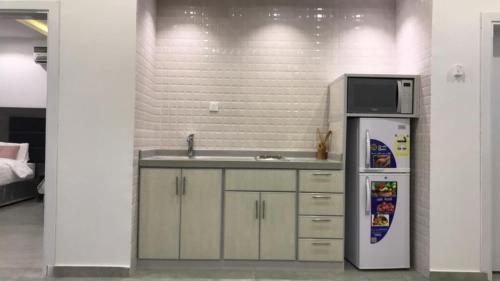 a kitchen with a sink and a microwave and a refrigerator at Rawaat Ghaym in Taif