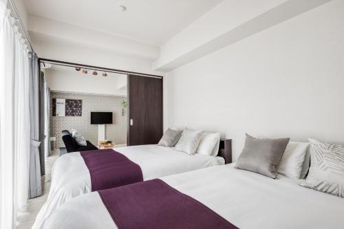 two beds in a room with white and purple at BON Condominium Umeda in Osaka