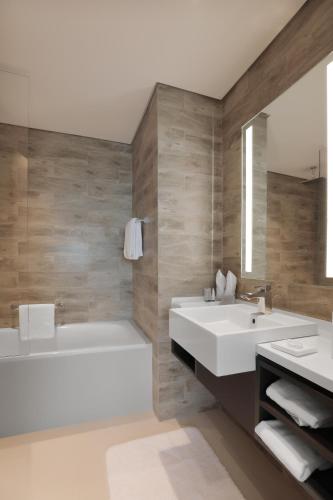 a bathroom with two sinks and a tub and a mirror at Millennium Executive Apartments Mont Rose in Dubai