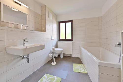 ein Badezimmer mit einem Waschbecken, einer Badewanne und einem WC in der Unterkunft Reetdachhaus "Treibholz" in Wiek auf Rügen 