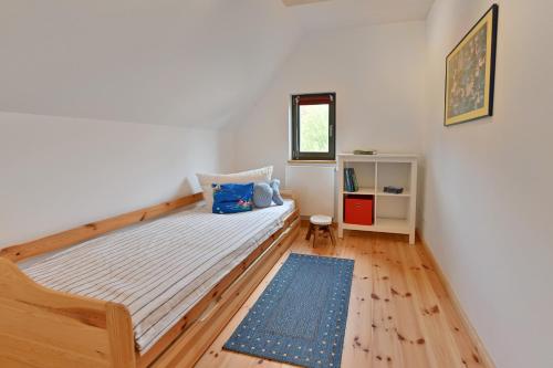 ein kleines Schlafzimmer mit einem Bett und einem blauen Teppich in der Unterkunft Reetdachhaus "Treibholz" in Wiek auf Rügen 