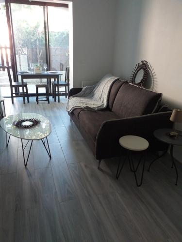 een woonkamer met een bank en 2 tafels bij Joli studio res au calme en rez de jardin à Bandol. in Bandol