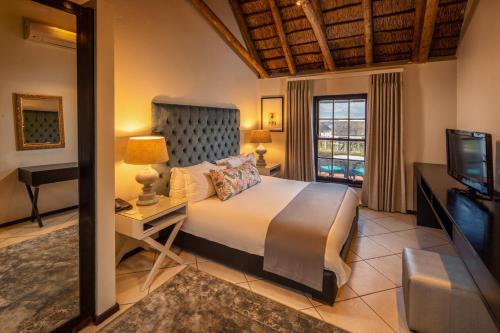 een slaapkamer met een groot bed en een televisie bij Grande Roche Hotel in Paarl