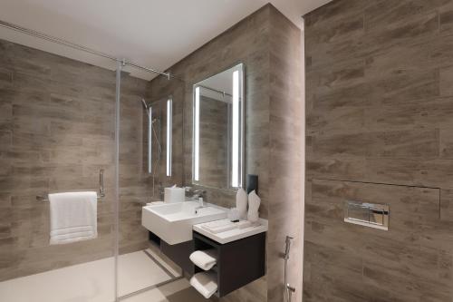 a bathroom with a sink, mirror, and bath tub at Millennium Montrose Hotel Apartment in Dubai