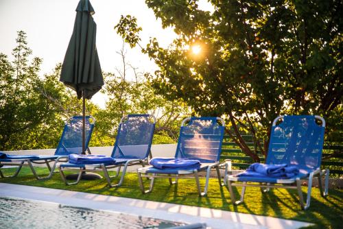 a group of chairs and an umbrella next to a pool at Anemos Villa in Sálakos