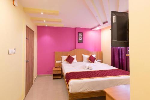 um quarto com uma cama com uma parede rosa em Sree Comforts em Kushalanagar