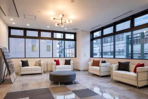 a lobby with white chairs and a table and windows at Green Rich Hotel Tottori Ekimae (Artificial hot spring Futamata Yunohana) in Tottori