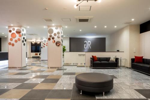 a lobby with couches and a chair in a building at Green Rich Hotel Tottori Ekimae (Artificial hot spring Futamata Yunohana) in Tottori