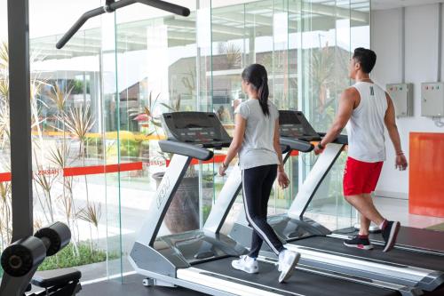 a man and a woman on a treadmill in a gym at HARRIS Hotel and Conventions Denpasar Bali in Denpasar