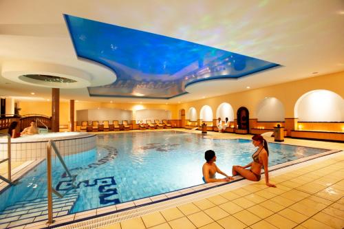 a hotel pool with two people sitting in the water at Hotel ESPERANTO Kongress- und Kulturzentrum Fulda in Fulda